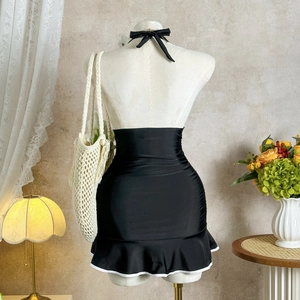 Detail view of high waist black swimsuit with white ruffle trim on a mannequin