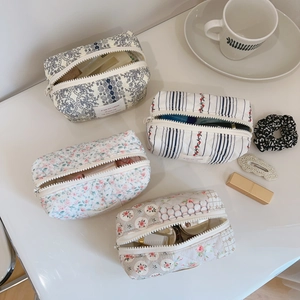 Detailed overhead view of four quilted floral cotton makeup bags with zipper closures