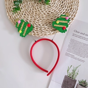 Festive Christmas headband with green glitter trees and colorful pompoms on white surface