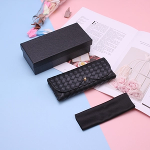 Detail of black woven leather eyeglass case set with gold snap button and packaging box