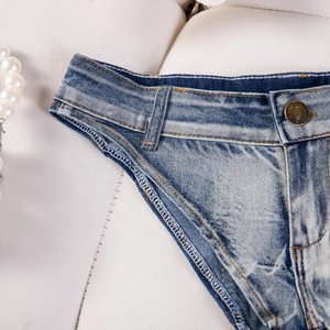 Macro di pantaloncini di jeans celeste che mostra il bottone in metallo e la trama lavata