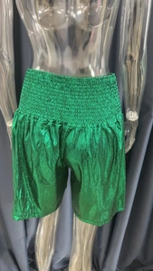 Detail view of metallic green high waist elastic shorts with pleated texture and shimmer