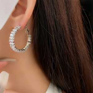 Close-up of silver hoop earrings with rectangular cubic zirconia on female model