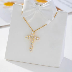 Detail view of a gold cross pendant necklace with clear zircon stones on a white stand