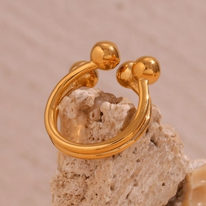 Macro shot of gold-plated stainless steel double-row open ring on a beige coral stone