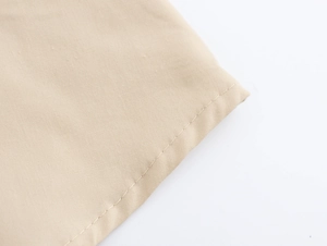 Gros plan sur les coutures détaillées et la texture du tissu de la robe beige