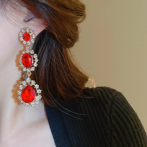 Gros plan de boucles d'oreilles pendantes à trois niveaux avec pierres rouges et cristaux
