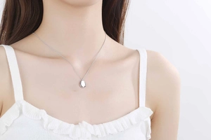 Close-up of minimalist S925 sterling silver water drop pendant on woman's neckline