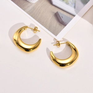 Detailed close-up of chunky gold C-shaped hoop earrings with a polished metallic finish