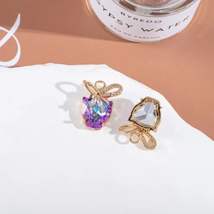 Macro detail of purple-blue gradient crystal heart earrings with gold bow accents
