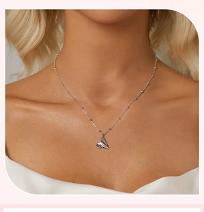 Close-up of 925 sterling silver paper plane necklace with blue sapphire on a model