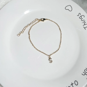 Detailed close-up of a 18K gold-plated bracelet with a zircon-set S-letter pendant