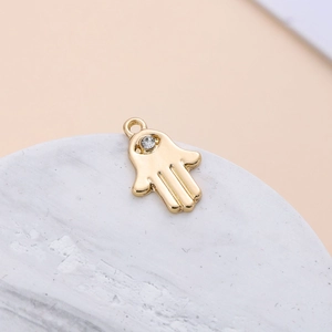 Detailed close-up of a golden Hamsa hand pendant with a sparkling crystal stone