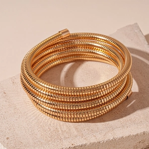 Detailed view of a gold multi-layer snake chain bracelet on a textured stone base