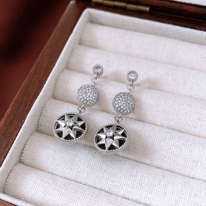 Détail de boucles d'oreilles argentées avec motif étoile noire et cristaux brillants