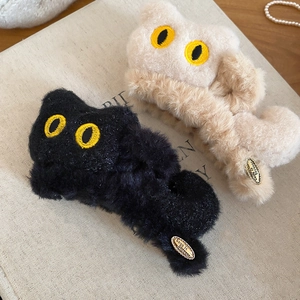 Détail de pinces à cheveux chat en peluche noire et beige avec une texture douce et soyeuse