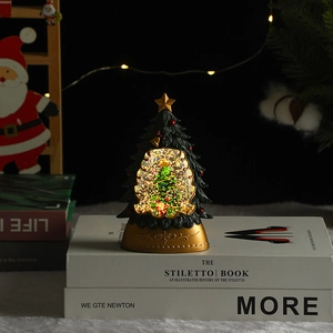 Détail d'une boule à neige sapin de Noël lumineux avec socle doré et paillettes