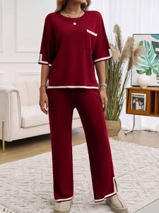 Détail de l'ensemble en tricot bordeaux avec liseré blanc, poche poitrine et fente de jambe