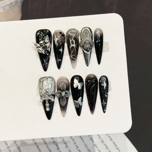 Handmade press-on nails with black goth designs, silver skulls, and cross nail art charms