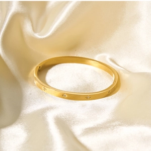 Detailed view of 18k gold stainless steel starburst bangle with zircon on cream satin
