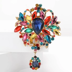 Gros plan d'une broche vintage dorée avec pierres multicolores et cristal bleu en poire