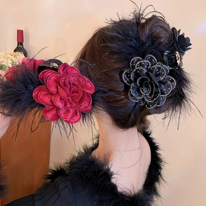 Detail of red fabric rose hair claw with delicate feathers and rhinestones for elegant styling