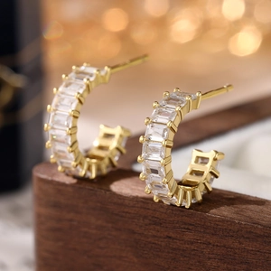 Macro shot of 925 silver gold-plated C-shaped earrings with clear zircon stones