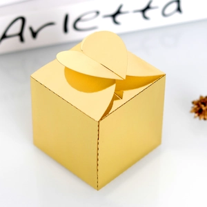 Détail d'une boîte à bonbons dorée avec dessus en cœur pour mariages et fêtes