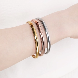 Polished minimalist gold, rose gold and silver stainless steel bangles set on wrist