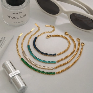 Detail of stacked gold plated tennis bracelets with multi-colored rectangular gemstones