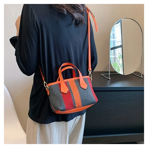 Striped canvas crossbody bag in grey, orange, and red shown on a female model