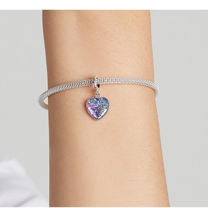 Macro detail of heart-shaped charm with iridescent fish scale pattern on mesh bracelet