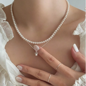 Double-layered 925 sterling silver bow and pearl necklace shown on a model neck