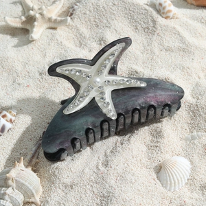 Pince à cheveux étoile de mer avec strass et perles sur sable de plage naturel