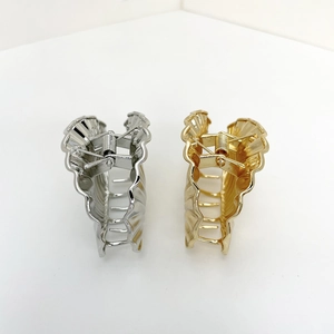 Detail of shell-shaped metal hair claws in polished gold and silver metallic finishes