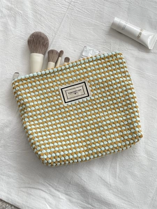 Detailed close-up of blue and brown checkered knit makeup bag with zipper closure