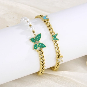 Detail of gold Cuban chain bracelets with green enamel butterfly charms and pearls