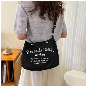 Black canvas tote bag with white lettering and silver buckle in minimalist style