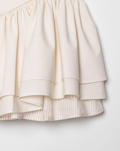 Detail of beige tiered ruffle mini skirt showing layered design and fine striped lining