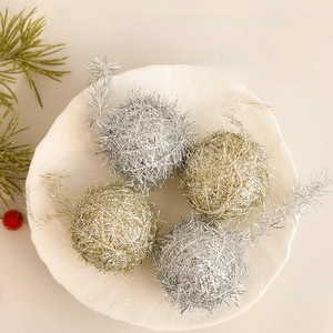 Set of 4 gold and silver Christmas wool balls on a white plate with pine decorations