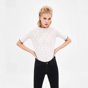 Elegante top in pizzo bianco a maniche corte con collo alto e motivi floreali traforati