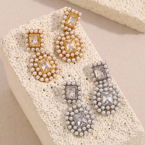 Detailed macro view of 18K gold and silver earrings with rectangular zircon and pearls