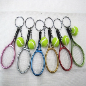 Detailed view of six colorful mini tennis racket and ball keychains on white grid background