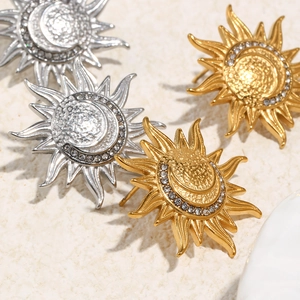 Macro detail of sun and moon stud earrings with zircon inlay in gold and silver finish