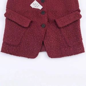 Deep red bouclé wool jacket with black buttons and textured finish in a flat lay view