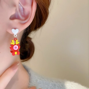 Gros plan de boucles d'oreilles dragon avec clous cœur blanc pour un style festif chic