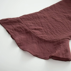 Detailed close-up of wine red pleated fabric texture and stitching on a lace-up blouse