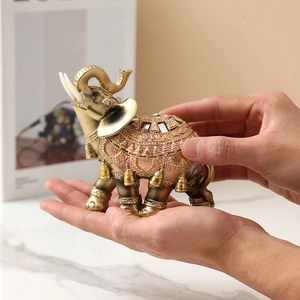 Macro view of a hand holding a decorative gold and copper resin elephant with ornate carvings