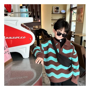 Close-up of kids chest bag paired with a wave pattern knit polo sweater in a cafe