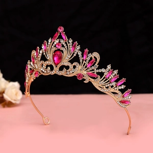 Detailed side view of luxury gold crown with pink gems and crystals on pink surface